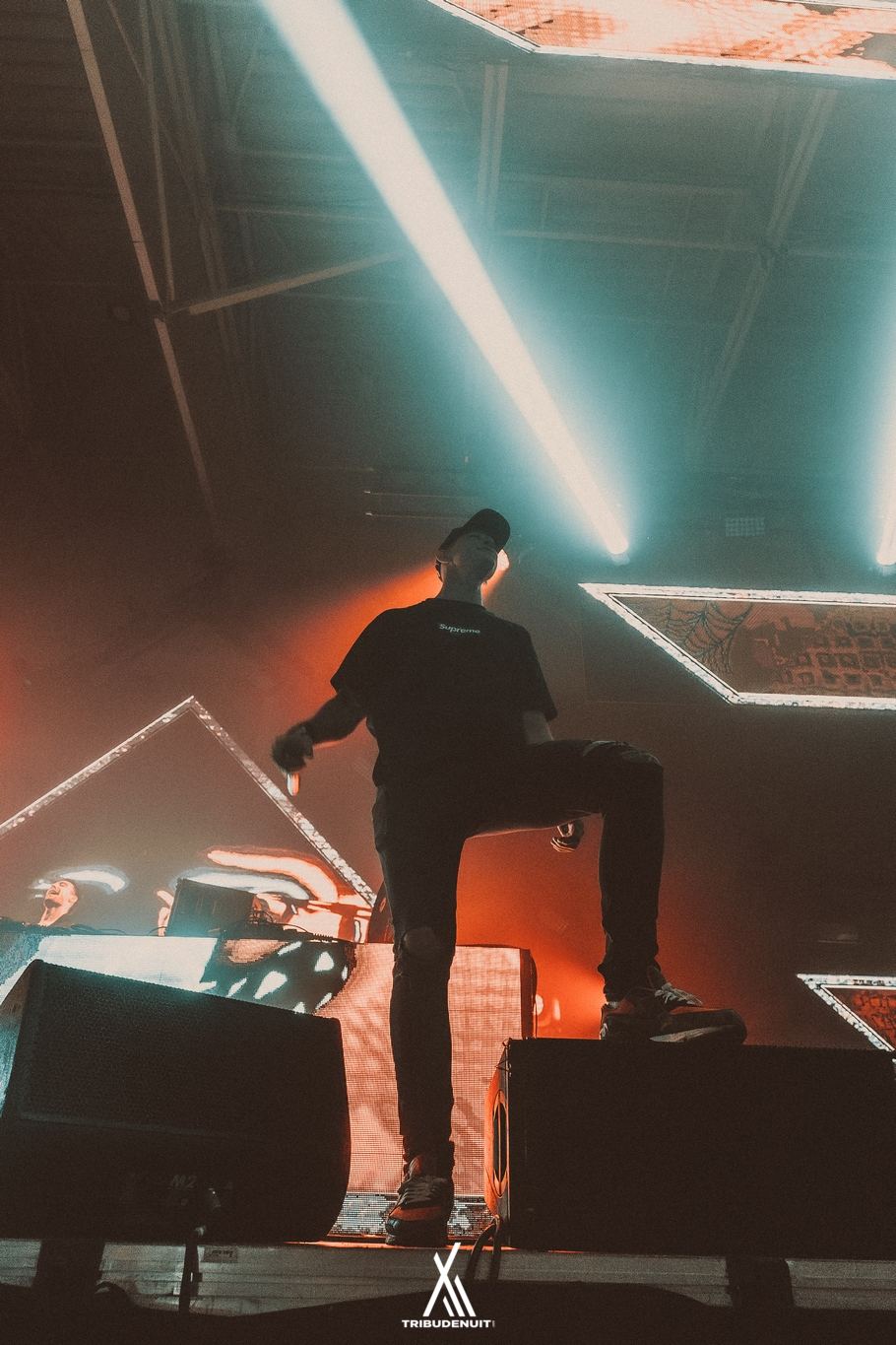 Une personne debout sur un caisson de scène sous des faisceaux lumineux obliques lors d'un concert – DREAM NATION FESTIVAL